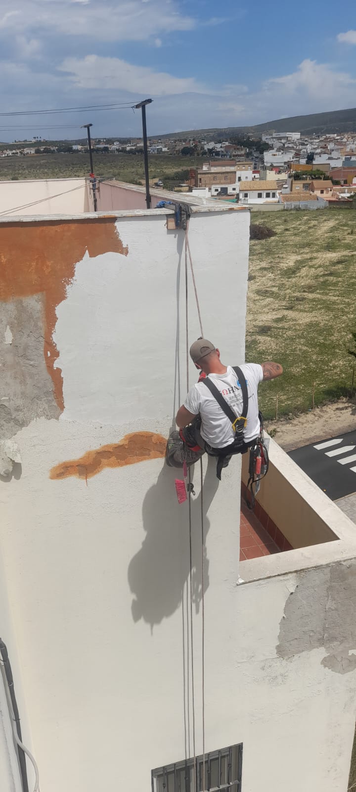 Técnico pintando una fachada usando arneses